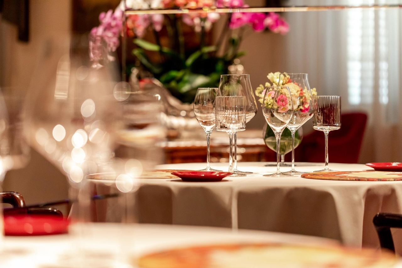 A table set with crystal glasses and orchids in the dining room at Enoteca Pinchiorri