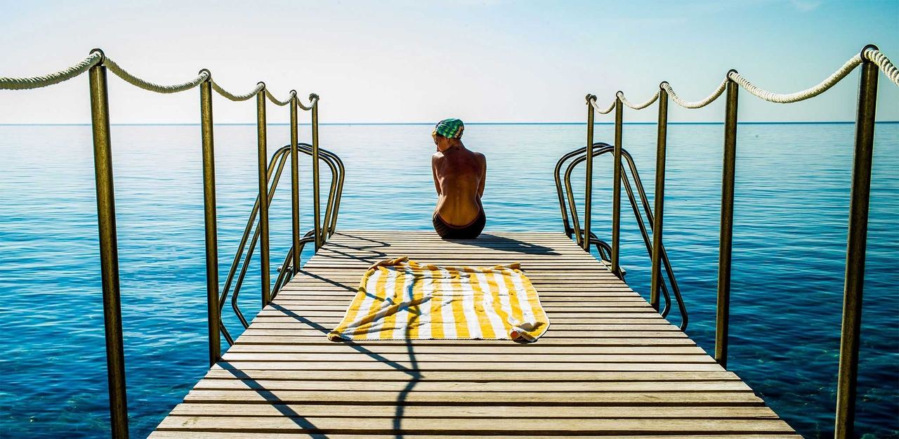 A swimmer on the jetty at Il Pellicano, above the clear sea of the Argentario