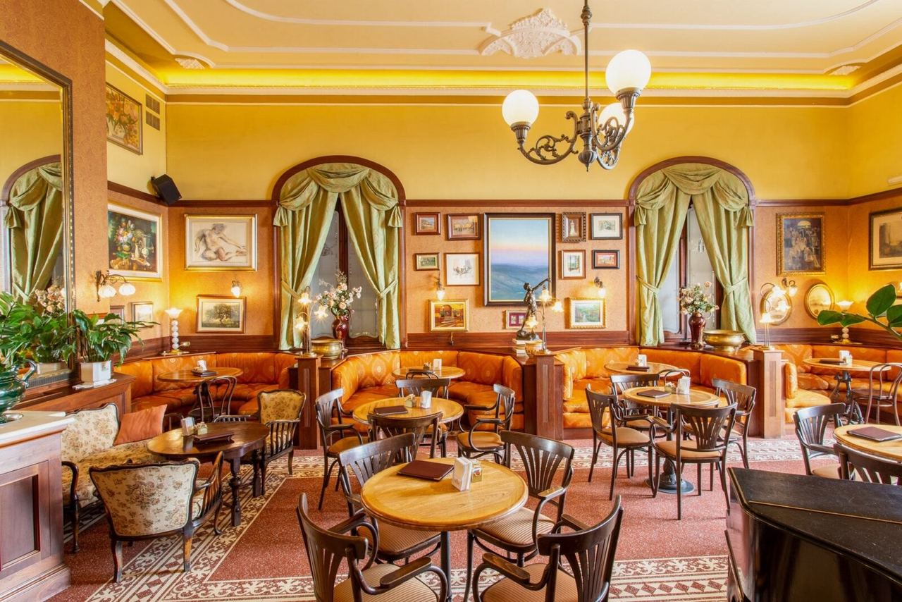 The Caffè Poliziano’s main room in Montepulciano, with velvet banquettes, framed paintings and green curtains