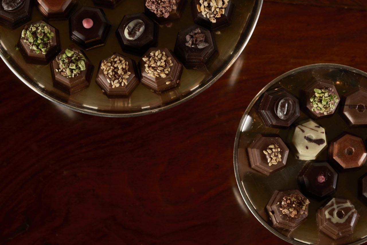 Rivoire’s hand-made chocolates on glass dishes on a dark wooden table